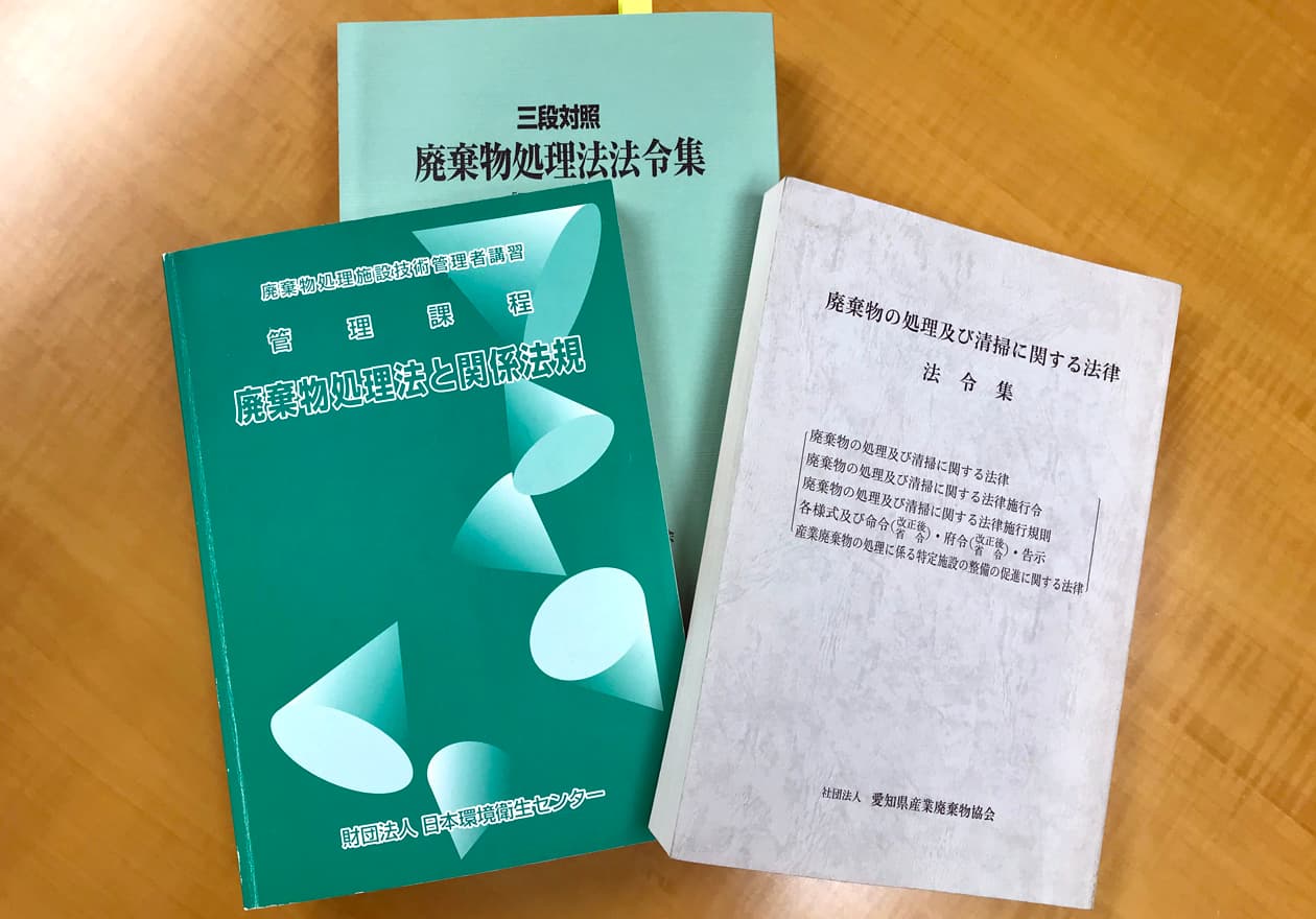 廃棄物処理法の教本を持つ竹内の様子